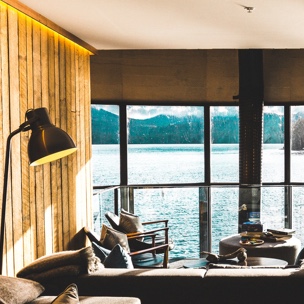 A living room facing outward to a stunning view of a lake, with a mountain range off in the distance.